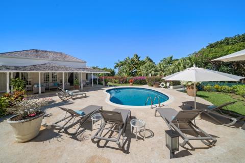 Private pool deck with sun loungers, umbrellas, and lush tropical gardens at Ixora, Royal Westmoreland, Barbados